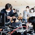 Một tình nguyện viên của Apple cầm micrô hỗ trợ chương trình Creative Studios ở Tokyo cùng với các thành viên của Sankakusha.