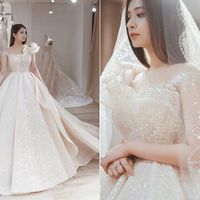 Váy cưới đính 12.000 viên đá pha lê Swarovski của nàng dâu xứ Huế Linh Chi được làm hoàn toàn bằng vải ren dệt cùng sợi đá để cô dâu thực sự tỏa sáng và lộng lẫy trong ngày trọng đại. Phần vai áo bất đối xứng là điểm nhấn đặc biệt và tôn nét điệu đà, nữ tính cho nàng dâu.