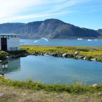 Bể nước nóng gần hồ và núi vào một ngày nắng ở Uunartoq, Greenland
