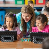Giáo viên Lindsay Barnes giảng dạy bằng iPad cho hai học sinh lớp 1 tại Học Khu Thống Nhất Downey trong lớp học.