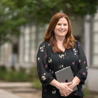 Jennifer Robbins, giám đốc giáo dục tiểu học của Học Khu Thống Nhất Downey kiêm vai trò Apple Learning Coach, đang cầm iPad đứng ngoài trời.