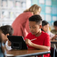 Một học sinh nhỏ tuổi tại Học Khu Thống Nhất Downey đang sử dụng iPad trong lớp học.