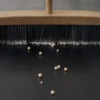 Nina Canell: Mother of Dust, 2023, pearls, broom, modified conveyer belt, 275 5/8 by 41 3/8 by 41 3/4 inches.
