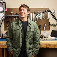 Mike Huish, Giám Đốc Điều Hành của Huish Outdoors, đứng trước băng ghế làm việc với nhiều công cụ và thiết bị lặn.