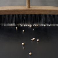 Nina Canell: Mother of Dust, 2023, pearls, broom, modified conveyer belt, 275 5/8 by 41 3/8 by 41 3/4 inches.