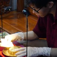Quá trình dát vàng lên bánh trung thu cần sự tỉ mỉ và khéo léo (Ảnh: Xuân Nghiệp)