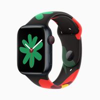 Hình ảnh Apple Watch Series 9 với dây đeo trong Bộ Sưu Tập Black Unity và mặt đồng hồ mới; trong hình ảnh này, mặt đồng hồ có một bông hoa màu xanh lá nhỏ hơn.