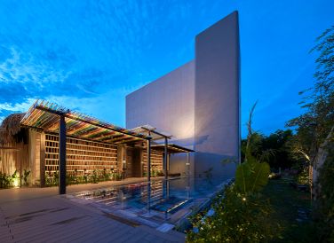 Mặt tiền hướng Tây tạo điểm nhấn với "lớp áo" gạch ngói đỏ, mái lợp lá, giúp cản nắng gắt. Những "lỗ thở" được tạo ra giúp đón gió, đưa không khí trong lành vào không gian bên trong.