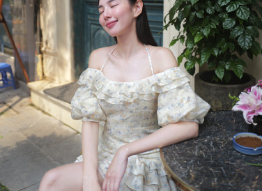 Thùy Tiên xuống phố cà phê cùng bạn bè cùng chiếc váy hoa nhí có gam màu trang nhã. Thiết kế xếp bèo nhún buộc dây giúp hoa hậu tôn phần xương quai xanh.