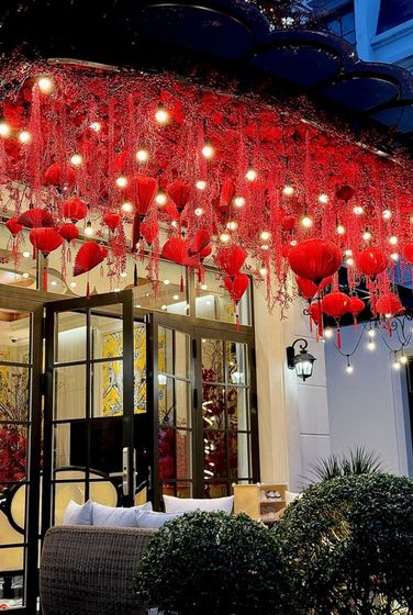 Mái hiên trước cửa nhà treo đèn lồng và rất nhiều đông đào màu đỏ rực.
