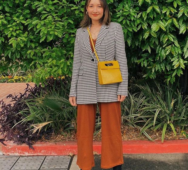 Áo blazer họa tiết là món thời trang nổi bật nhưng không kém phần thanh lịch. Anna Trương đã nâng tầm vẻ sang xịn mịn cho phong cách khi kết hợp áo blazer họa tiết gingham với áo len mỏng và quần ống suông mang tông màu nâu. Đôi boots tông màu đen là mảnh ghép lý tưởng của bộ trang phục. Chiếc túi màu sắc không khiến tổng thể bị rối mắt, trái lại còn giúp vẻ ngoài thêm tươi trẻ.