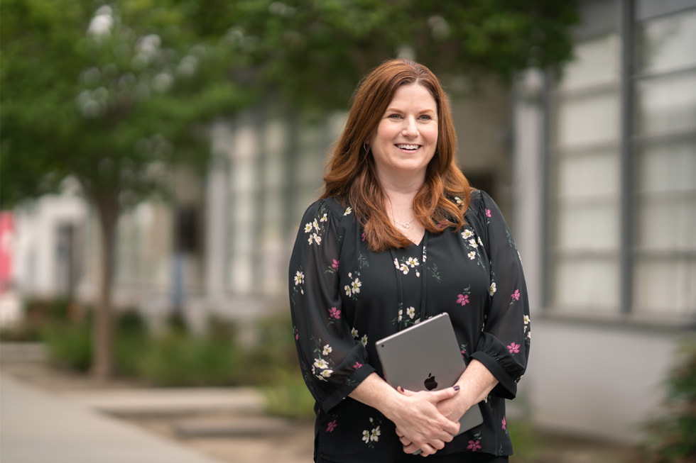 Jennifer Robbins, giám đốc giáo dục tiểu học của Học Khu Thống Nhất Downey kiêm vai trò Apple Learning Coach, đang cầm iPad đứng ngoài trời.