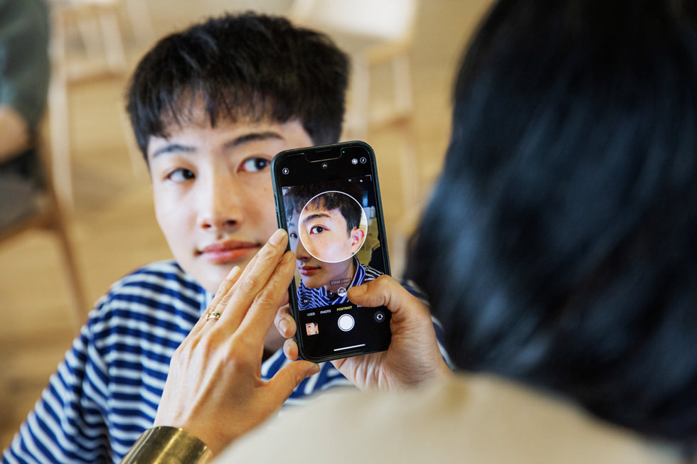 Một tình nguyện viên của Apple sử dụng một chiếc iPhone để hỗ trợ chụp ảnh với chương trình Creative Studios ở Tokyo.